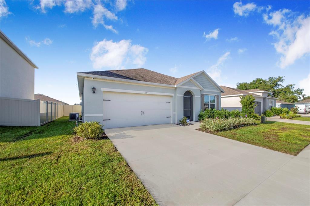 A light-colored single-story house with a two-car garage and a concrete driveway — 1704 FROGMORE AVENUE, HAINES CITY, FL