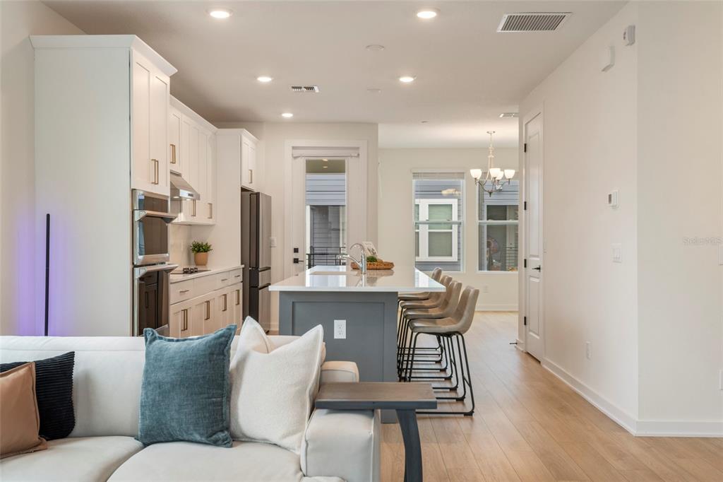 An entryway features light wood flooring, a carpeted staircase with a dark railing, and framed art — 12551 WILLSTATTER AVENUE, ORLANDO, FL