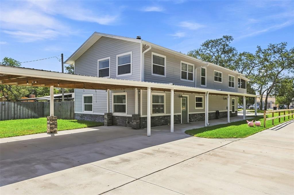 A two-story house with gray siding, a stone base, and a large attached metal carport — 1120 1ST AVENUE N, SAFETY HARBOR, FL