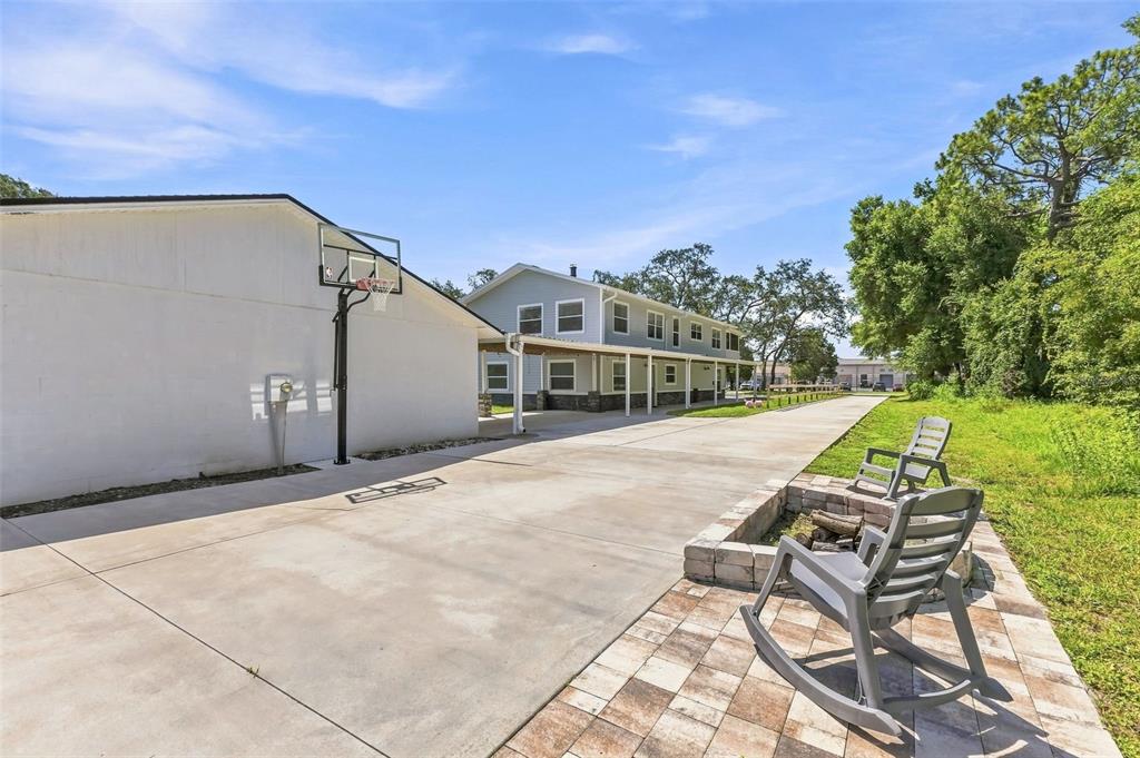 A concrete driveway leads to a two-story house with a basketball hoop and fire pit — 1120 1ST AVENUE N, SAFETY HARBOR, FL
