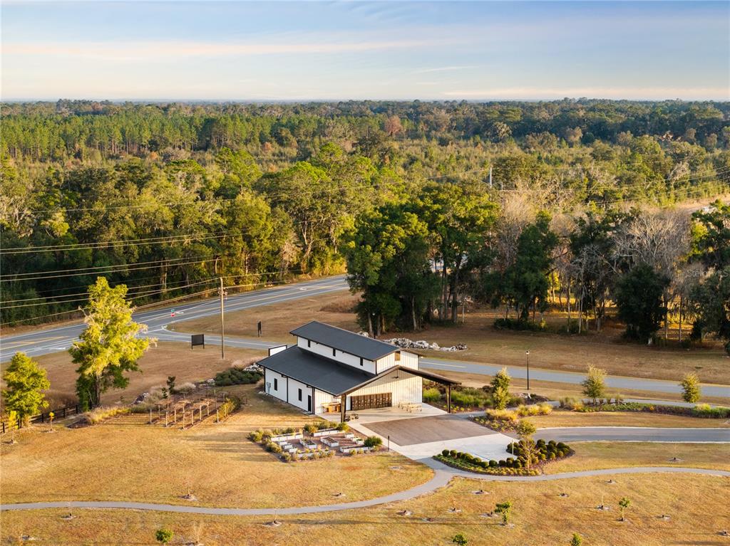 An aerial view shows a modern white barn-style building with a black roof near a road — Lot 46 SW 125TH CIRCLE, ARCHER, FL
