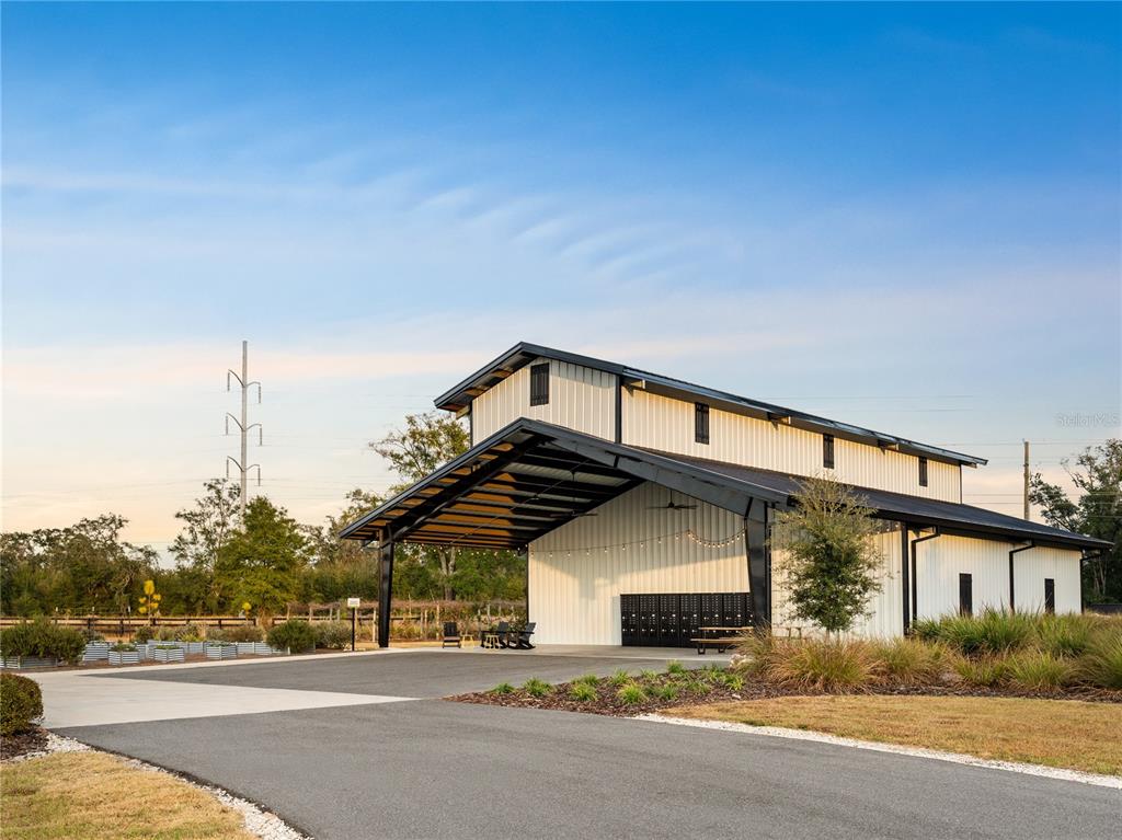 A modern white metal barn with a large covered patio and black structural framing — Lot 46 SW 125TH CIRCLE, ARCHER, FL