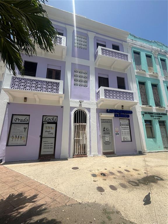 A three-story lavender building with white balconies and two ground-floor commercial storefronts — 260 CONSTITUCION, SAN JUAN, PR