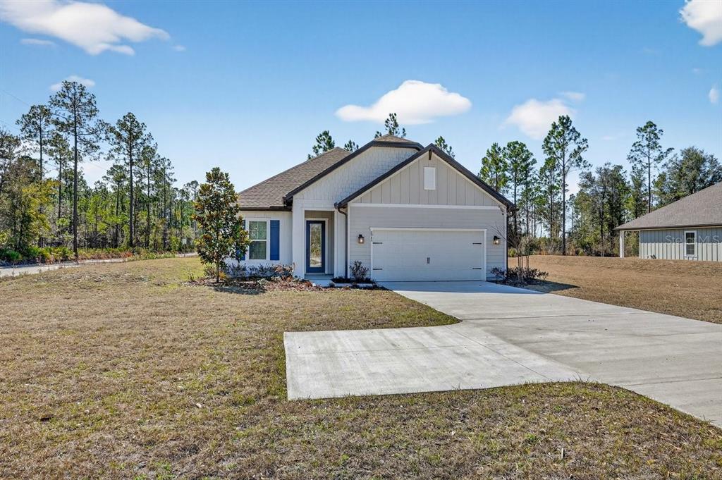 A single-story house with a light-colored exterior, a two-car garage, and a concrete driveway — 8719 FORD ROAD, BRYCEVILLE, FL