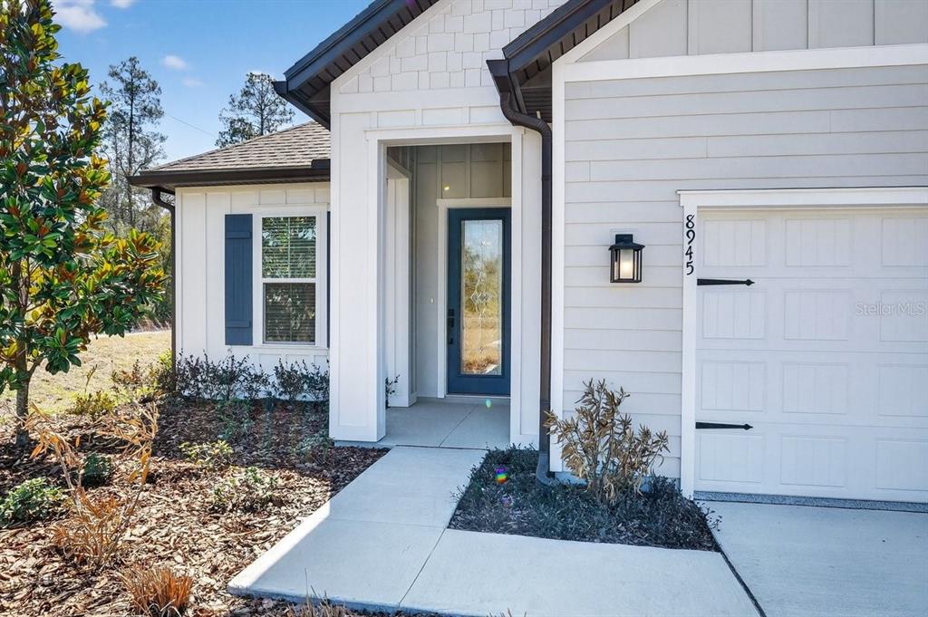 A modern house exterior features a blue front door, white siding, and a garage — 8719 FORD ROAD, BRYCEVILLE, FL