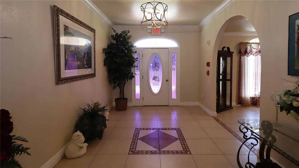 A bright entryway features tile flooring, a decorative front door, and a hanging light fixture — 7571 W HIGHWAY 326, OCALA, FL