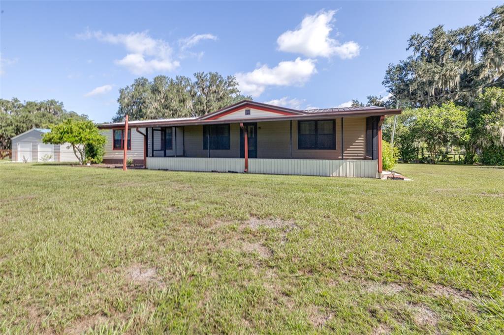 A single-story manufactured home with a screened front porch sits on a large grassy lot — 4605 THOMPSON ROAD, MULBERRY, FL