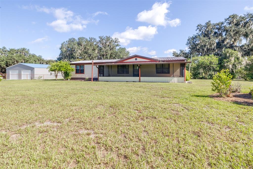 A single-story house with a metal roof and a screened porch sits on a lawn — 4605 THOMPSON ROAD, MULBERRY, FL