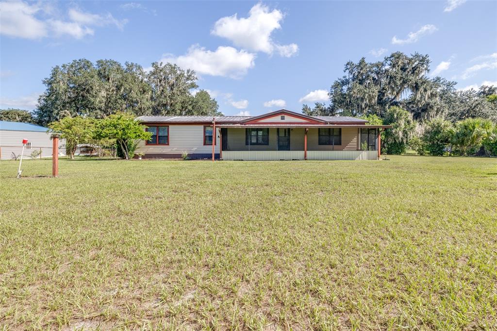 A single-story house with a covered front porch sits on a large, grassy lot — 4605 THOMPSON ROAD, MULBERRY, FL