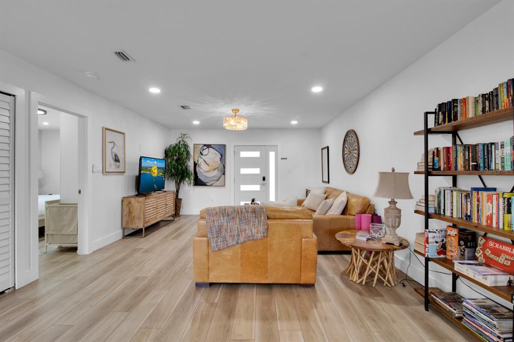 A living room features a tan leather sofa, a wooden bookshelf, and light wood flooring — 1155 LEMON BLUFF ROAD, OSTEEN, FL