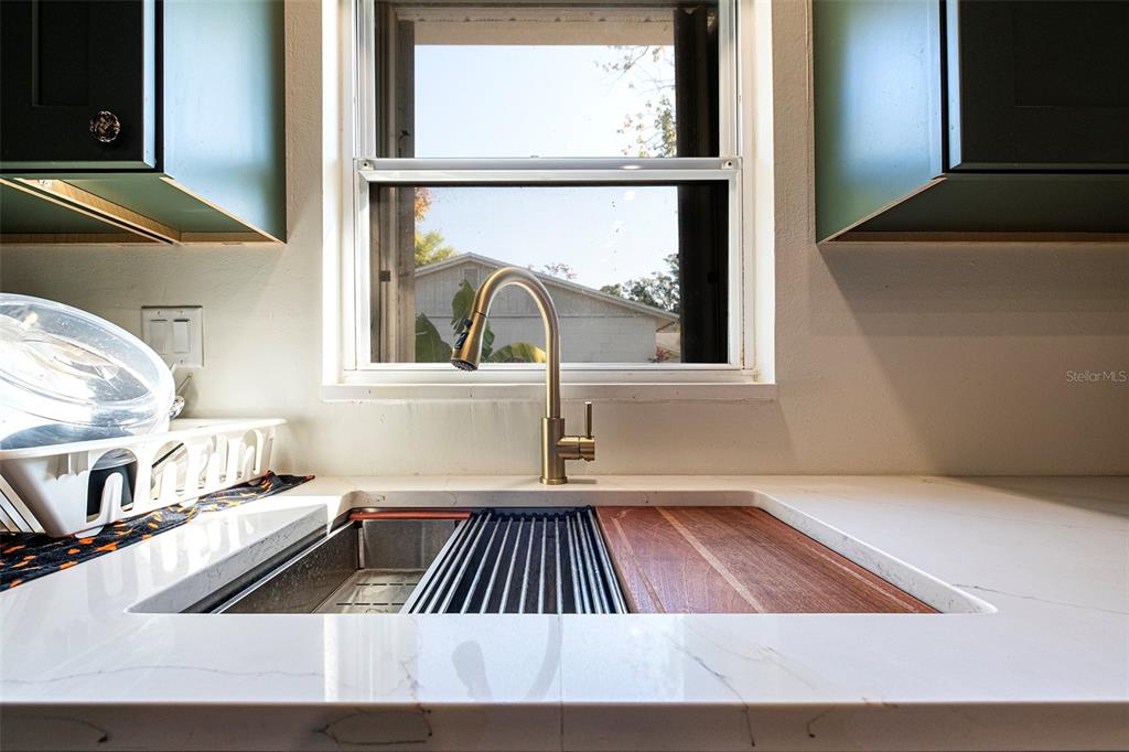 A kitchen sink with a gold faucet is set into a white marble countertop — 6401 CEDARBROOK DRIVE S, PINELLAS PARK, FL