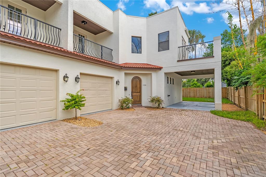 A two-story stucco house features a brick paver driveway, two garage doors, and a balcony — 134 E ESTHER STREET UNIT A, ORLANDO, FL