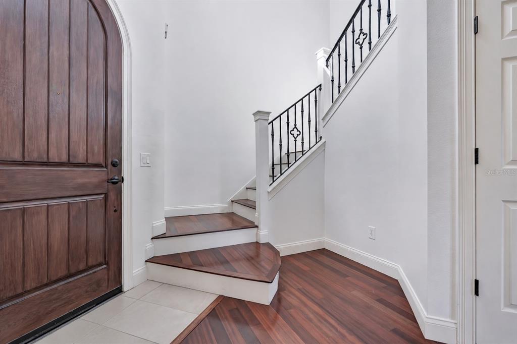 A foyer features a wooden arched door, a staircase with iron railings, and hardwood flooring — 134 E ESTHER STREET UNIT A, ORLANDO, FL