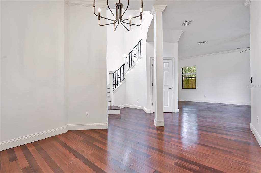 A bright foyer features dark hardwood floors, a modern chandelier, and a staircase with railings — 134 E ESTHER STREET UNIT A, ORLANDO, FL