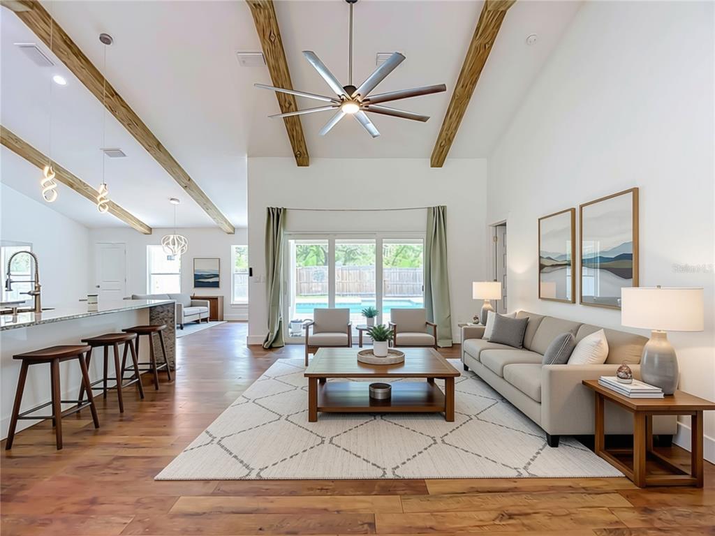 A living room with wood beams, a ceiling fan, and a view of a pool — 15032 HUMMINGBIRD ROAD, WEEKI WACHEE, FL