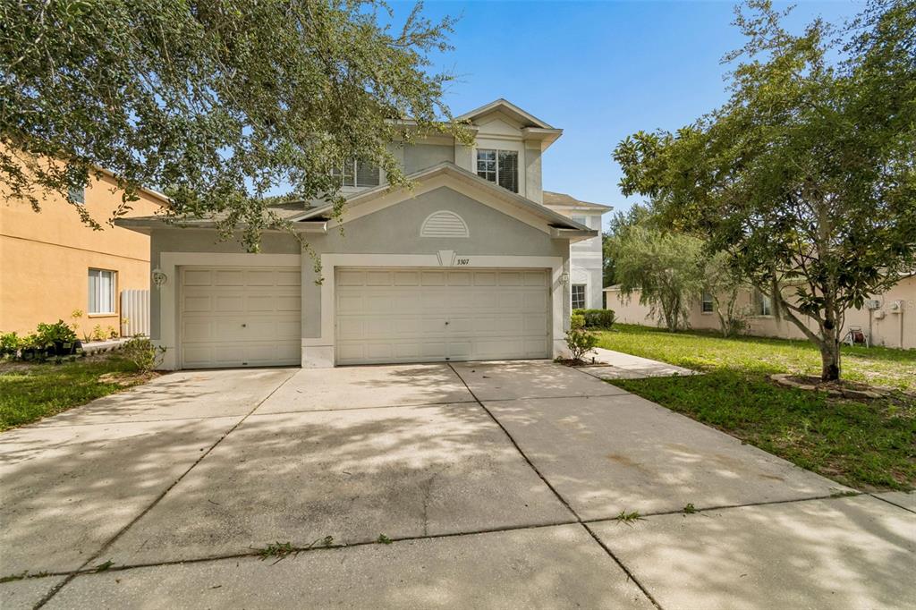A two-story house with a three-car garage and a concrete driveway under a clear sky — 3307 PINE TOP DRIVE, VALRICO, FL