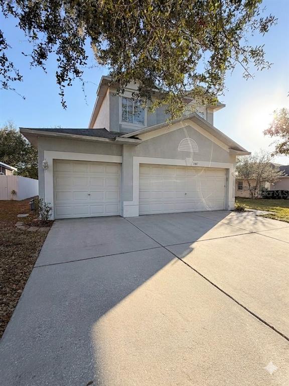 A two-story house with a three-car garage and a concrete driveway under a large tree — 3307 PINE TOP DRIVE, VALRICO, FL