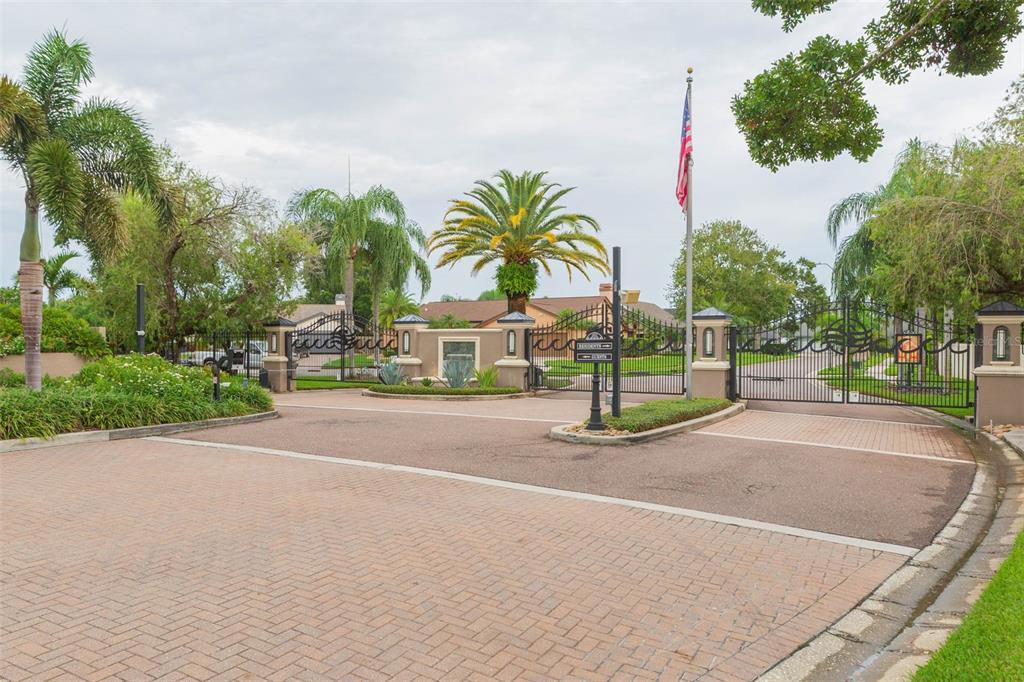 A gated entrance to a residential community features a paved driveway, palm trees, and landscaping — 4301 SALTWATER BOULEVARD, TAMPA, FL