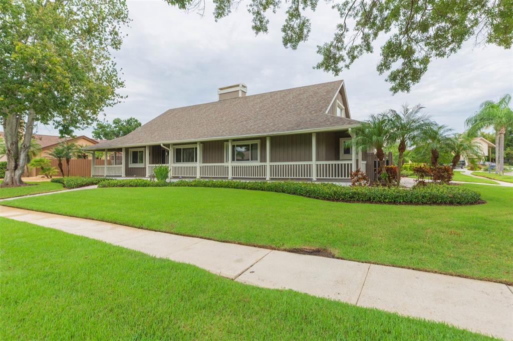 A single-story house with a wrap-around porch, brown siding, and a large front lawn — 4301 SALTWATER BOULEVARD, TAMPA, FL