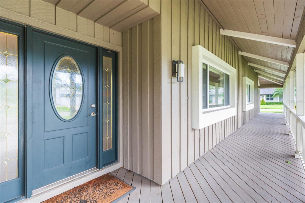 A blue front door with a glass oval insert opens onto a long wooden porch — 4301 SALTWATER BOULEVARD, TAMPA, FL
