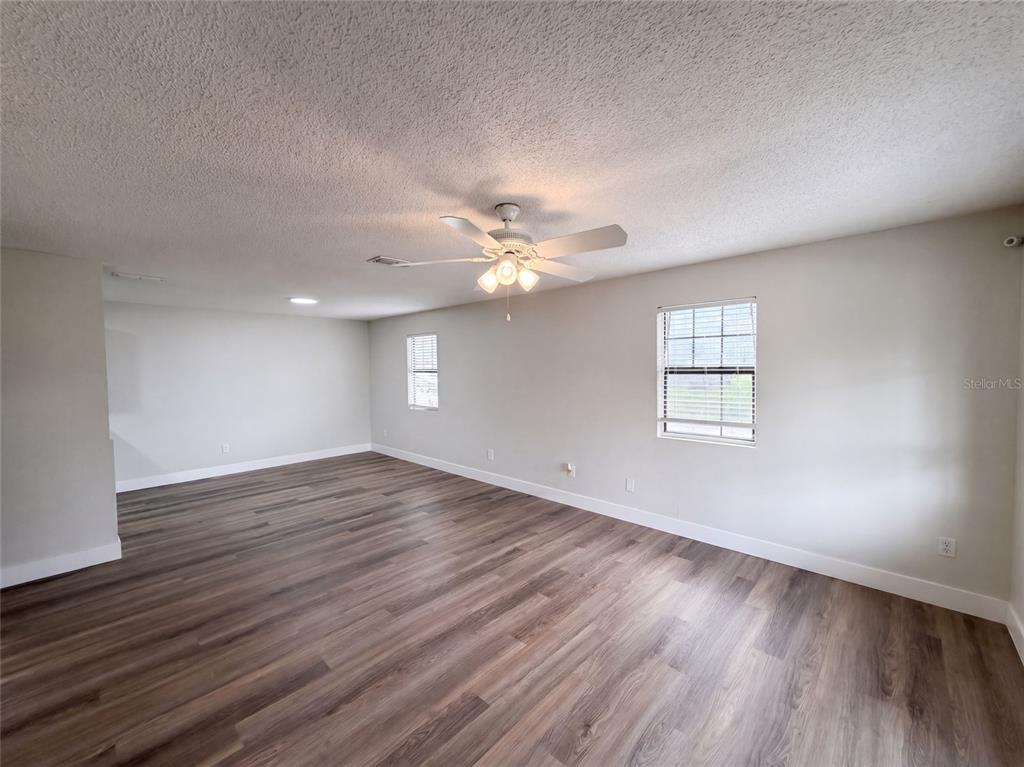 An empty room features light gray walls, wood-look flooring, and a ceiling fan — 9307 8TH AVENUE, ORLANDO, FL