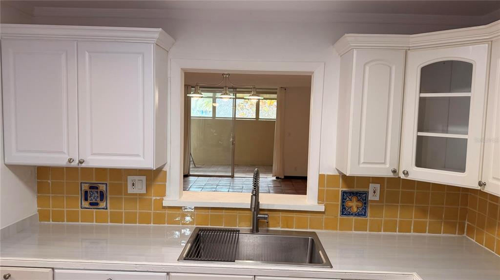 A kitchen features white cabinets, a stainless steel sink, and yellow square wall tiles — 406 NW 68TH AVENUE UNIT 107, PLANTATION, FL