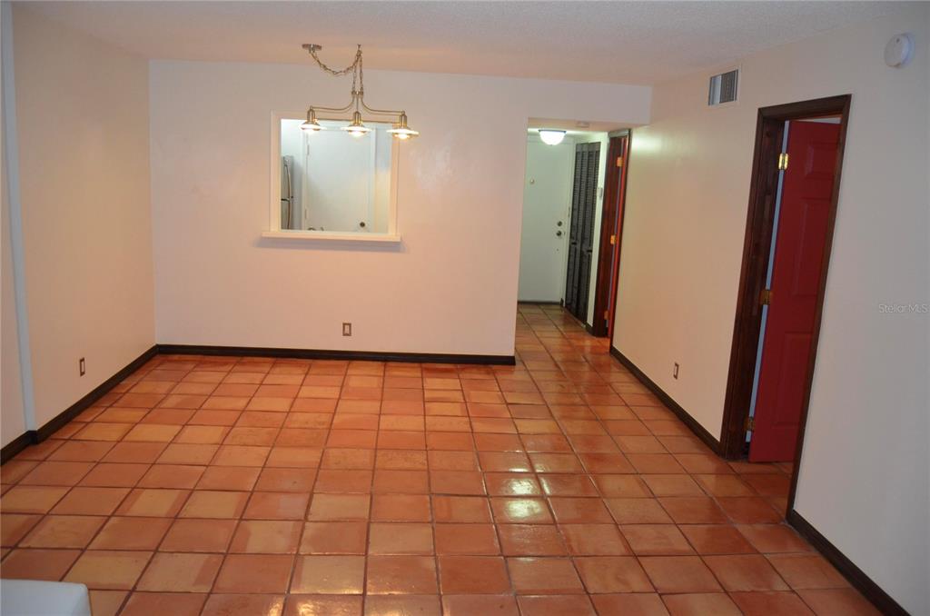 An empty dining area features terracotta floor tiles, a pass-through window, and a hanging light — 406 NW 68TH AVENUE UNIT 107, PLANTATION, FL
