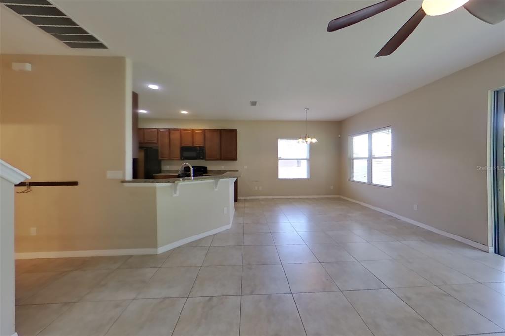 An open-concept kitchen and living area features tile flooring, wood cabinets, and a breakfast bar — 12552 HAMMOCK POINTE CIRCLE, CLERMONT, FL