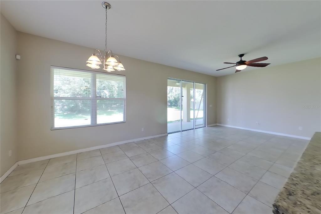 An open-concept dining and living area features light tile flooring, a chandelier, and sliding doors — 12552 HAMMOCK POINTE CIRCLE, CLERMONT, FL