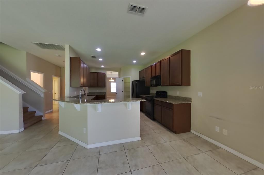 A kitchen with dark wood cabinets, granite countertops, and tile flooring — 12552 HAMMOCK POINTE CIRCLE, CLERMONT, FL