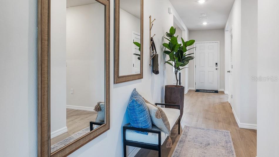 A bright entryway features a bench, mirrors, a potted plant, and light wood flooring — 13147 BENDING CREEK TRAIL, PARRISH, FL