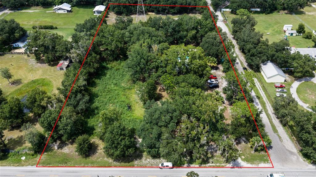 An aerial view shows a wooded lot outlined in red along a paved road — 7402 W KNIGHTS GRIFFIN ROAD, PLANT CITY, FL