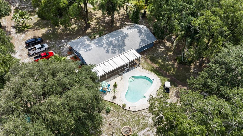 An aerial view shows a house with a pool, screened lanai, and three parked vehicles — 7402 W KNIGHTS GRIFFIN ROAD, PLANT CITY, FL