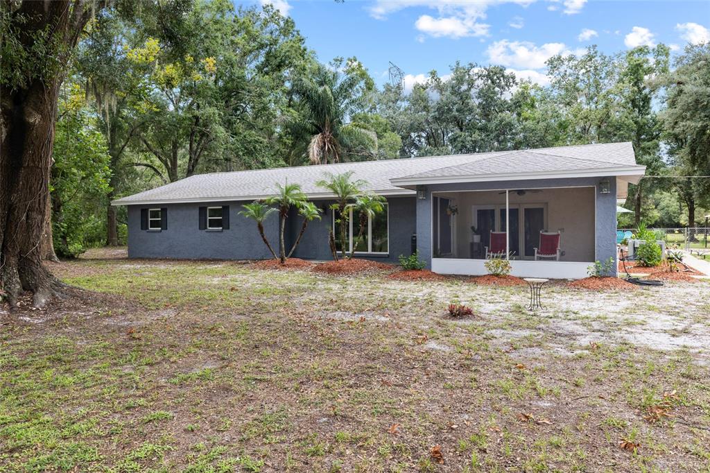 A single-story gray house features a screened-in porch and a large, partially wooded yard — 7402 W KNIGHTS GRIFFIN ROAD, PLANT CITY, FL