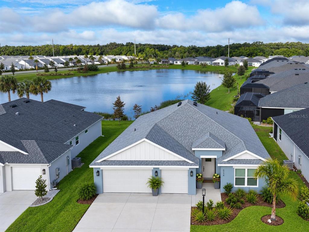 A screened-in patio features gray outdoor furniture, a coffee table, and views of a lake — 6244 HANNAN LOOP, THE VILLAGES, FL