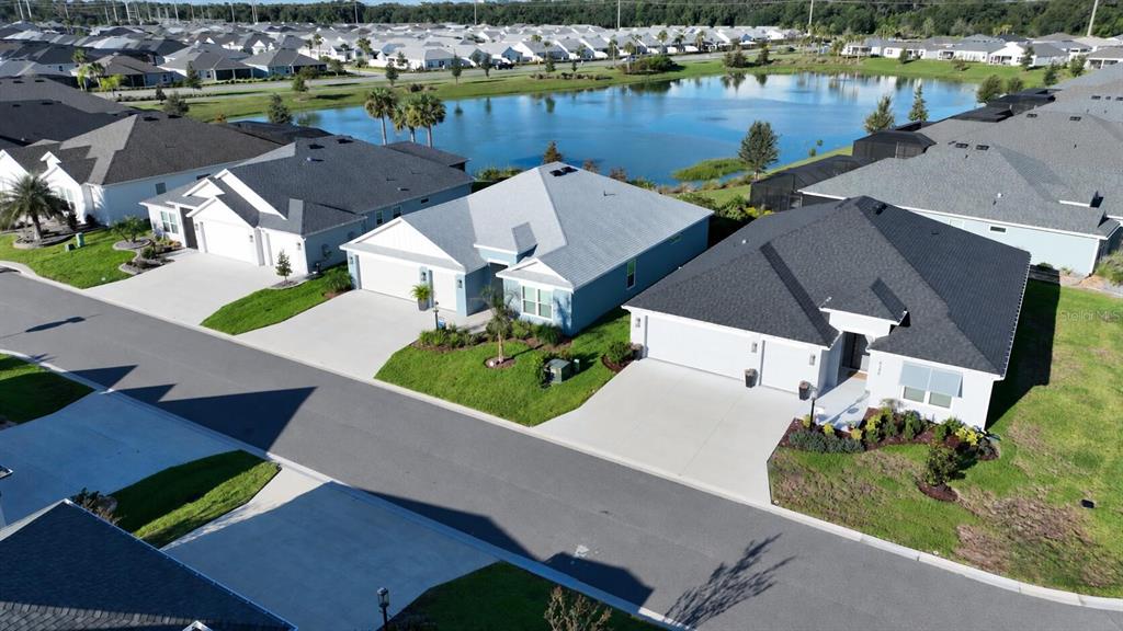 An open-concept living room features light wood-look flooring, a beige sofa, and two armchairs — 6244 HANNAN LOOP, THE VILLAGES, FL