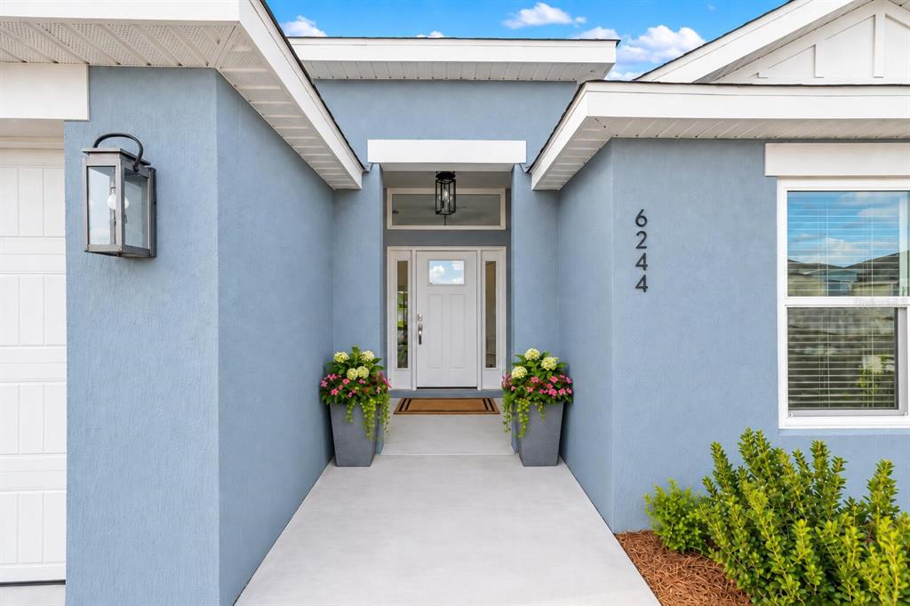 An open-concept living and dining area features light wood flooring, neutral furniture, and lake views — 6244 HANNAN LOOP, THE VILLAGES, FL