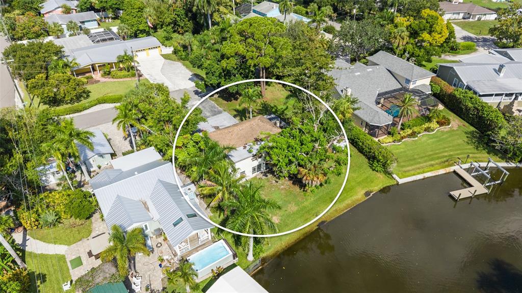 An aerial view shows a house circled in white, surrounded by trees and waterfront properties — 103 40TH STREET COURT NW, BRADENTON, FL