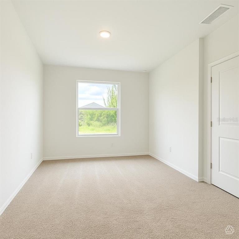 A bedroom with white walls, beige carpeting, a single window, and a closed white door — 12915 RED DEER PLACE, PARRISH, FL