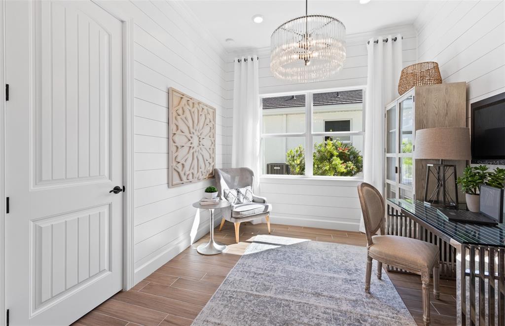 A home office features white shiplap walls, a crystal chandelier, and a glass-topped desk — 26641 BERING DRIVE, ENGLEWOOD, FL