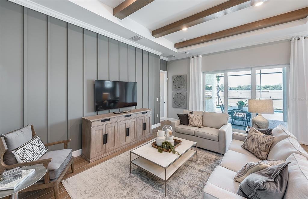 A living room features a gray board-and-batten accent wall, wood ceiling beams, and sliding doors — 26641 BERING DRIVE, ENGLEWOOD, FL