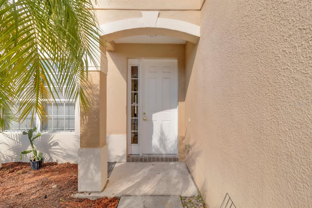 A white front door with a side window is set within a covered entryway — 2827 SAND ARBOR CIRCLE, ORLANDO, FL
