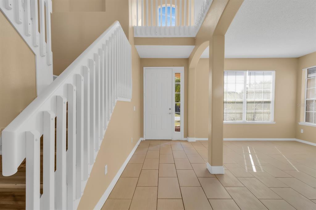 An entryway with tile flooring, a white staircase, and a view of an upper landing — 2827 SAND ARBOR CIRCLE, ORLANDO, FL