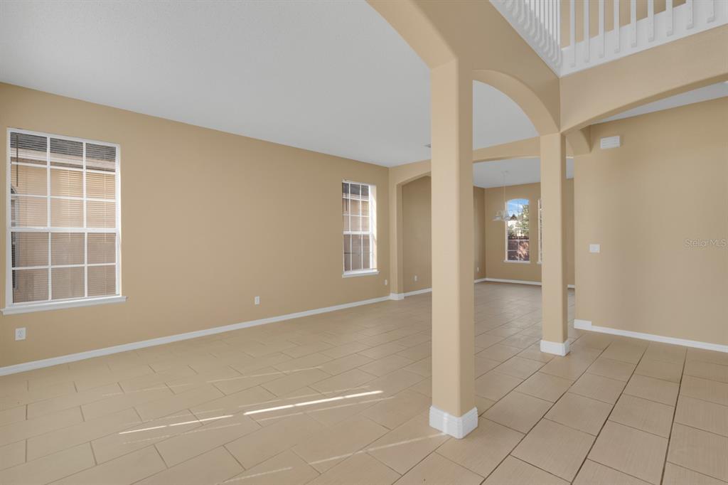 An open-concept living area features beige walls, light tile flooring, and arched architectural columns — 2827 SAND ARBOR CIRCLE, ORLANDO, FL