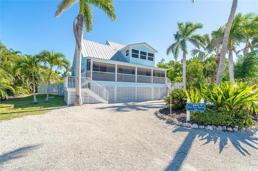 A light blue elevated house with a screened porch stands on a gravel driveway — 260 KETTLE HARBOR DRIVE, PLACIDA, FL