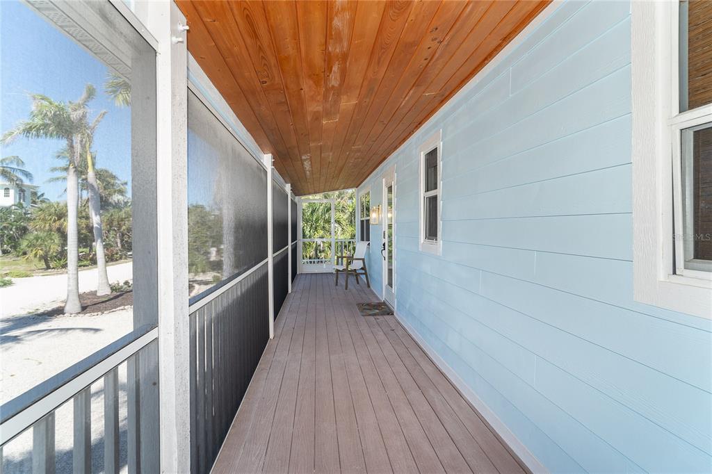 A long, covered porch with light blue siding, a wood ceiling, and a screened enclosure — 260 KETTLE HARBOR DRIVE, PLACIDA, FL