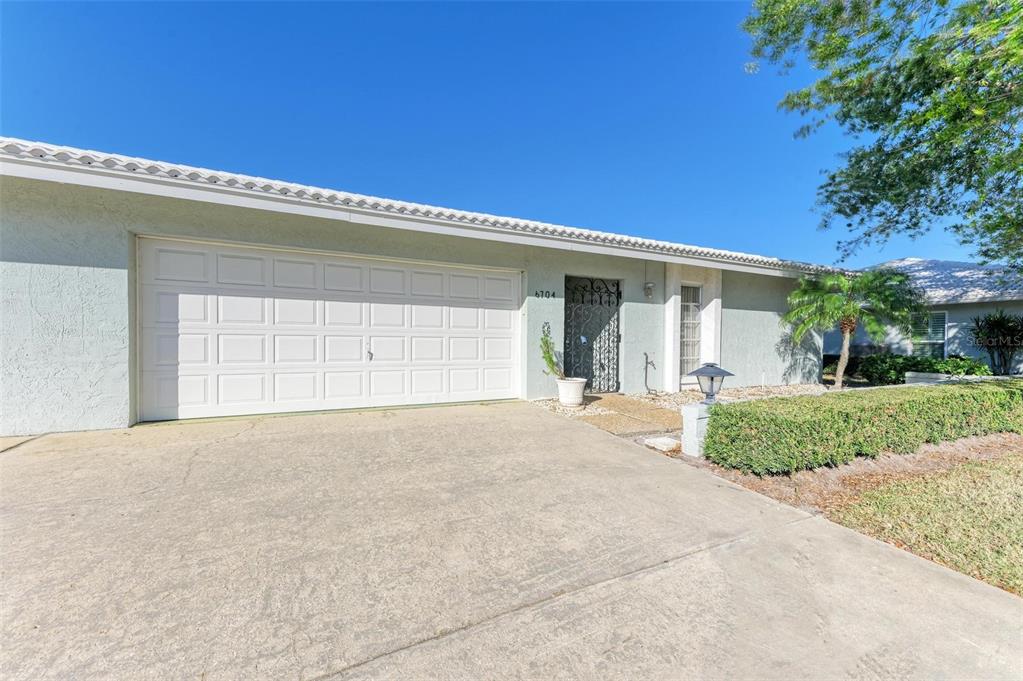 A single-story house with a white garage door, a decorative screen door, and a driveway — 6704 11TH AVENUE W, BRADENTON, FL