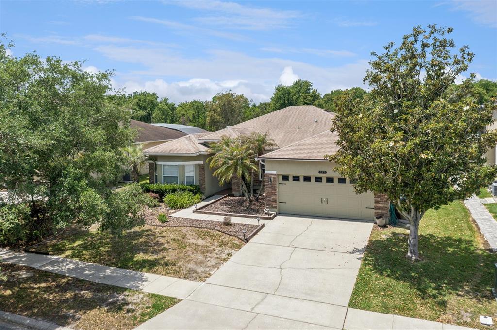 An exterior view of a single-story house with a two-car garage and a paved driveway — 237 STRATHMORE CIRCLE, KISSIMMEE, FL
