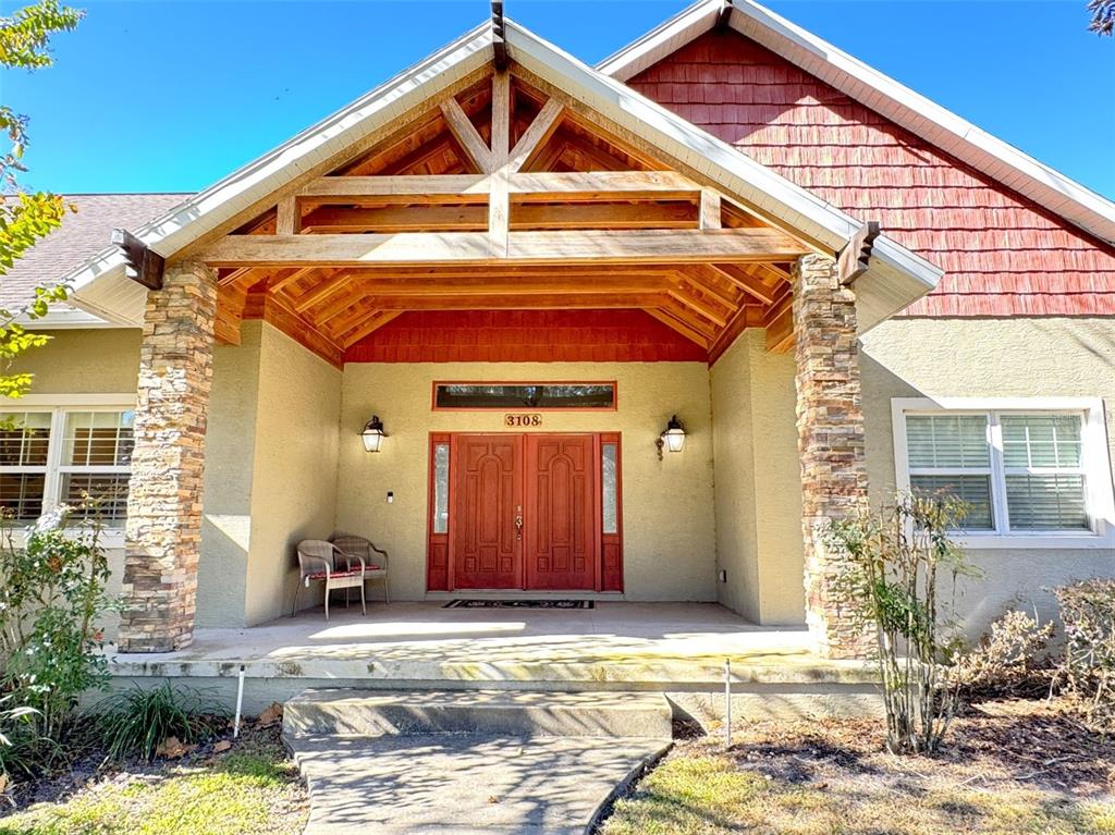 A front exterior view of a house featuring a covered porch with stone pillars — 3108 N WHEATON POINT, HERNANDO, FL