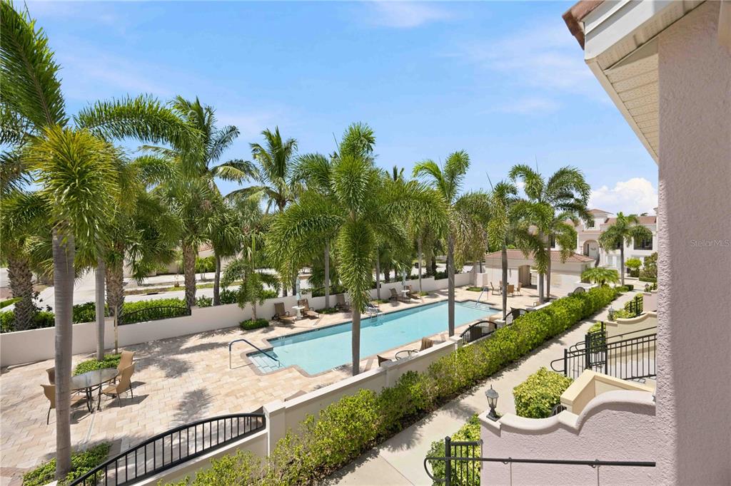 An aerial view shows a rectangular swimming pool surrounded by palm trees and paved patio furniture — 435 NOKOMIS AVENUE S UNIT 312, VENICE, FL